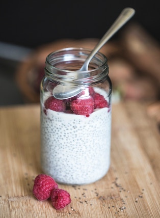 Yogurt parfait with chia seeds and raspberries in a glass jar.